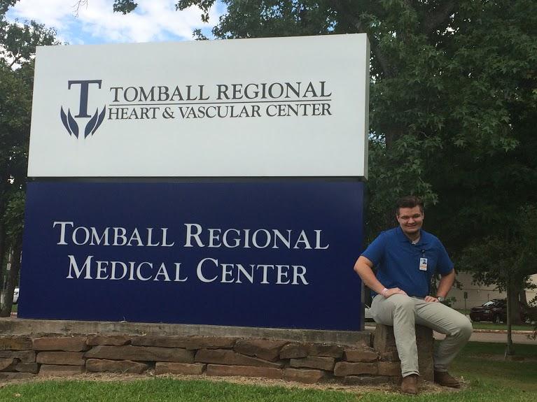 Garrett Henry sitting in front of the Tomball regional hospital sign. 
