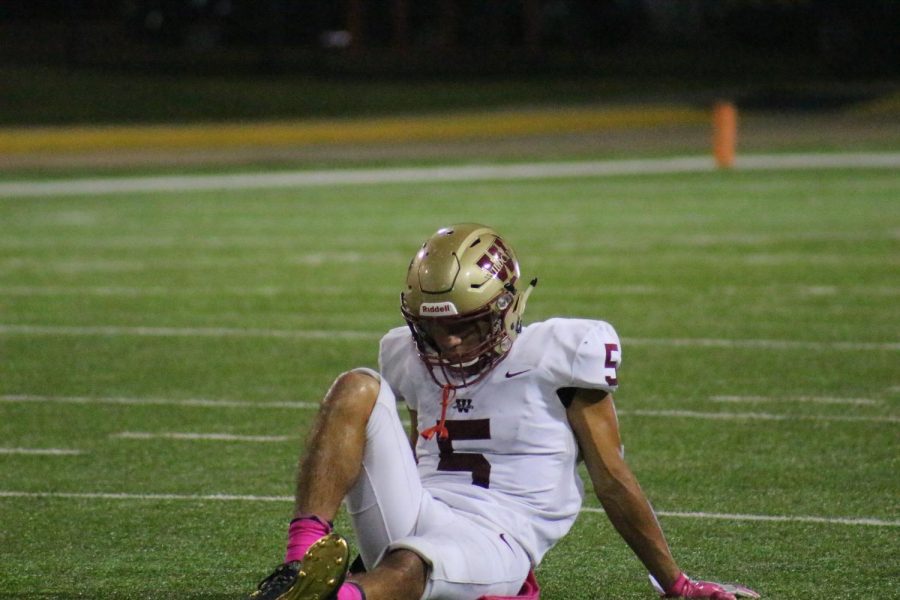 Running Back Jack Barrientez hangs his head as he rests on the field.