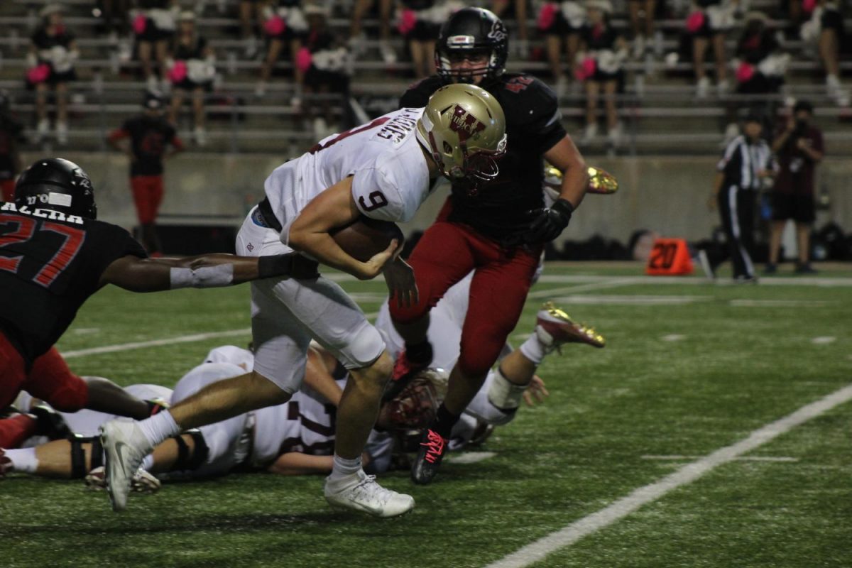 Quarterback Jackson Jones carries the ball while being pulled down during the first quarter.