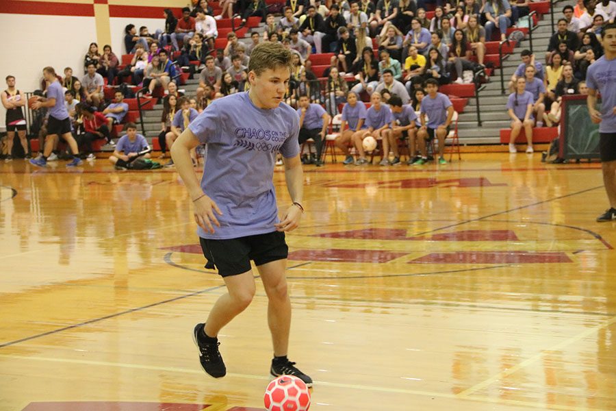 Senior Brady Sessions runs with the ball across the court during the soccer part of Chaos on the Court.