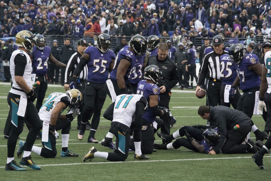 An NFL player from an injury and fellow players gather around.