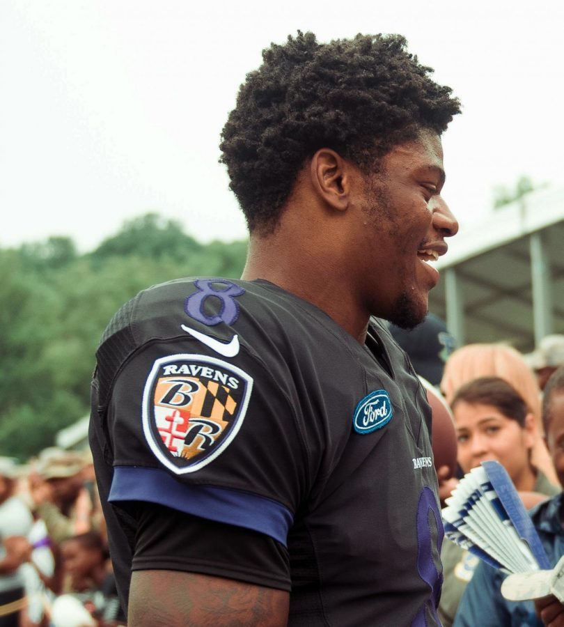 Quarterback Lamar Jackson shaking hands with multiple military officers