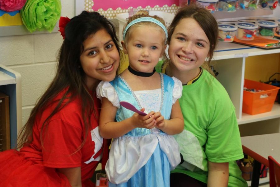 Student teachers, Desiree Diaz and Madison Webb interact with preschooler, Eliza, on Disney Character Day.