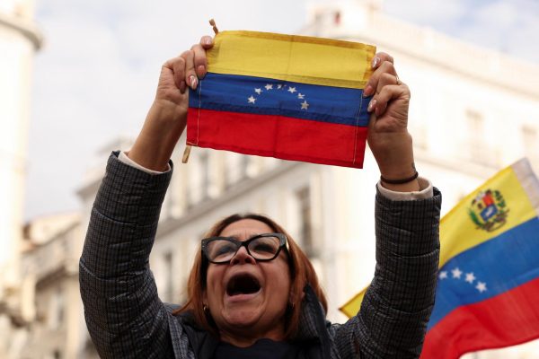 A person holds a Venezuelan flag, as people react to the news after U.S. President Donald Trump said the U.S. has struck Venezuela and captured its President Nicolas Maduro, in Madrid, Spain, January 3, 2026. REUTERS/Violeta Santos Moura